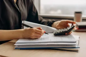 Smartfon z otwartym przelicznikiem walut euro–złoty na biurku obok monet euro i kart, w jasnym, domowym biurze.